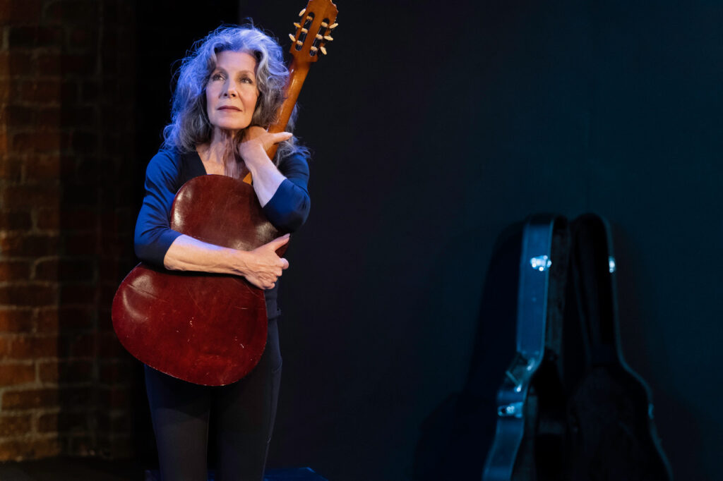 Committed A Ritual for Robbie — Lisa Robins embracing a guitar on stage