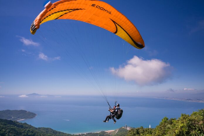 Skydiver descending with a colorful parachute against a clear blue sky.