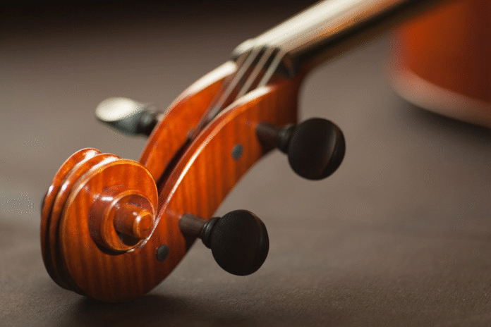 Close-up of a violin and bow on a wooden surface, symbolizing daily care and protection – Photo by Méline Waxx