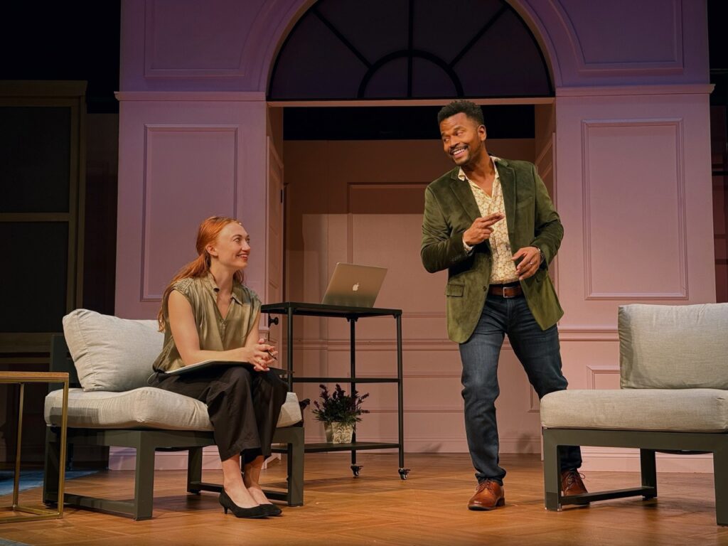 Two actors performing in I’ll Give You My Heart at the Colony Theatre, one seated and one standing during an intimate scene.