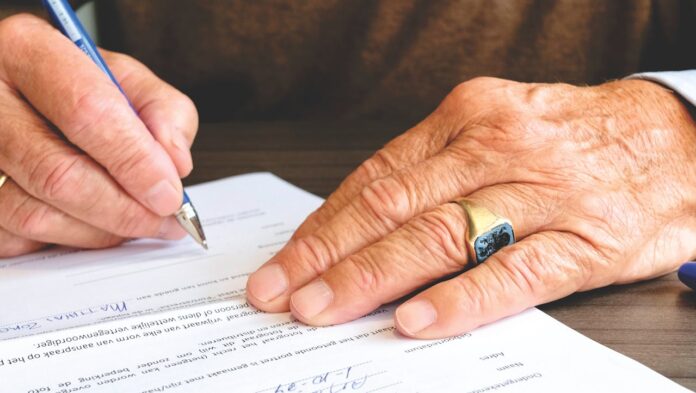 Person signing an insurance or legal document at a desk