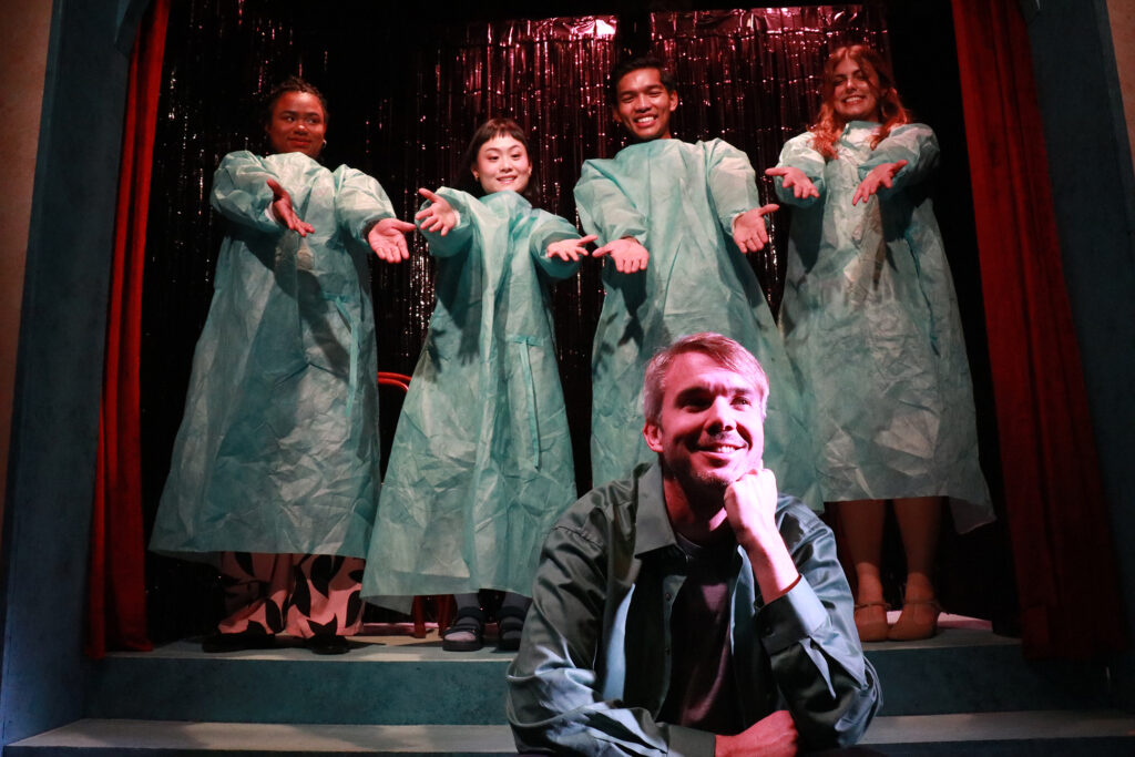 Cast members perform a satirical musical number in medical gowns in The Altruist at the Group Rep.