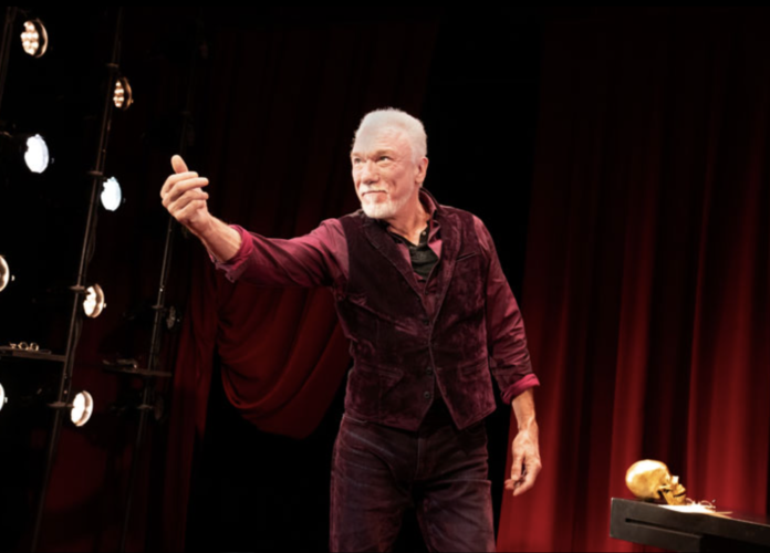 Patrick Page onstage in All the Devils Are Here reaching toward the audience