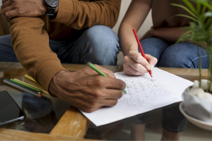 Couple coloring together at a table as a relaxing, screen-free activity.