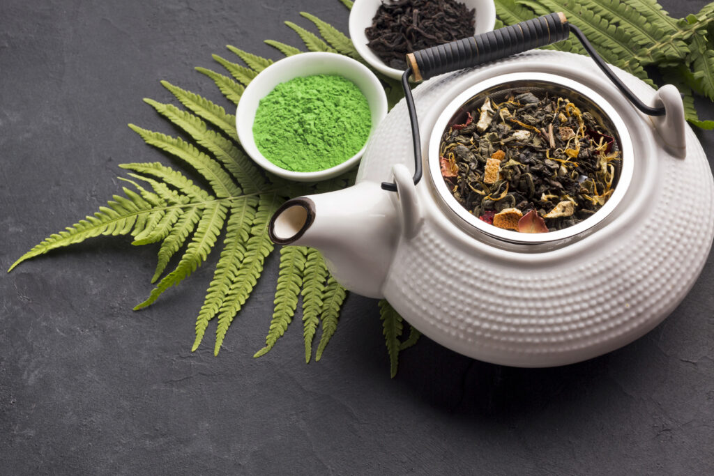 Kratom powder and dried botanical leaves arranged with a teapot