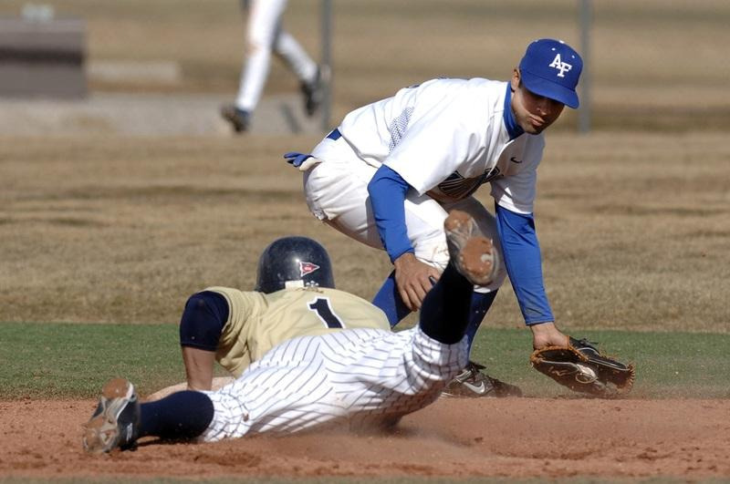 Baseball player slides into second base as infielder applies a tag, showing focus under pressure.
