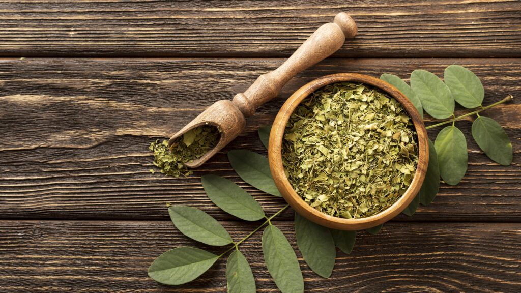 Crushed kratom leaves in a wooden bowl with scoop