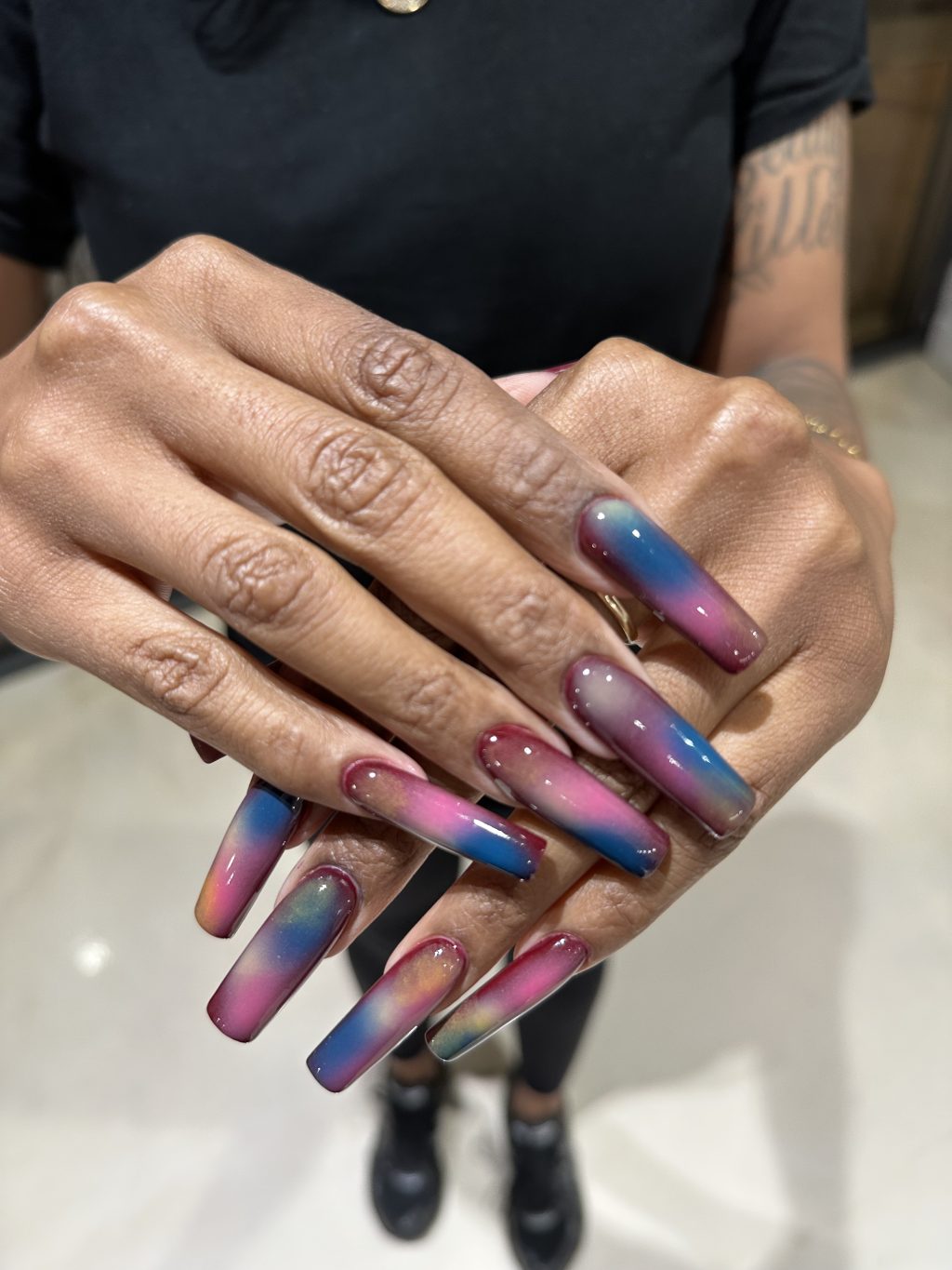 Long coffin-shaped nails with blended pink, blue, and purple ombré polish showcasing creative nail design at Beauty Haus NoHo