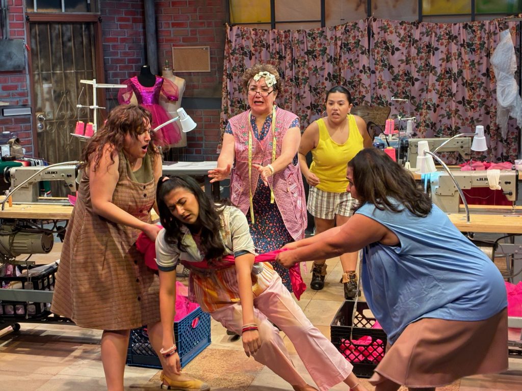 Real Women Have Curves stage production showing group of women in garment factory setting, one fainting from heat.