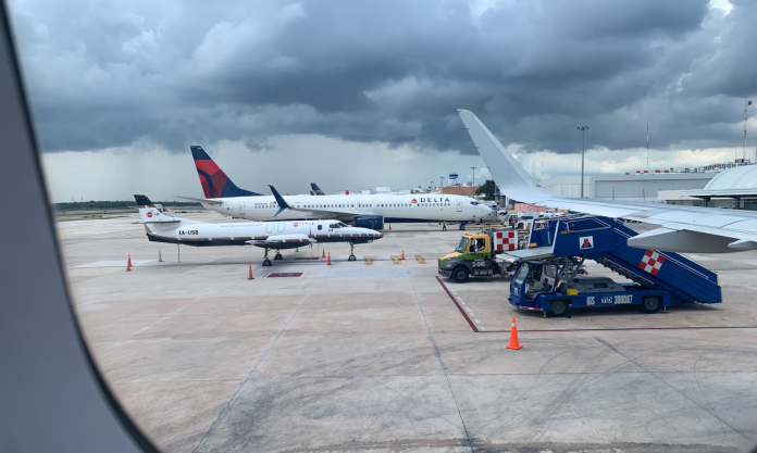 Cancun Airport runway with planes and storm clouds before transfer to Playa del Carmen