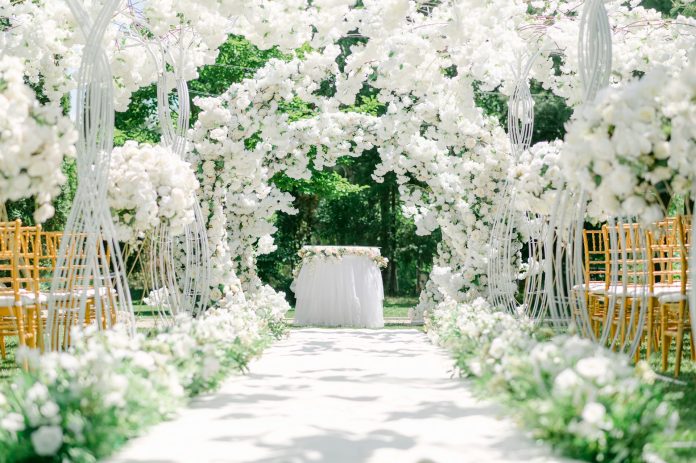 Outdoor wedding decorations with white floral arch and garden ceremony aisle