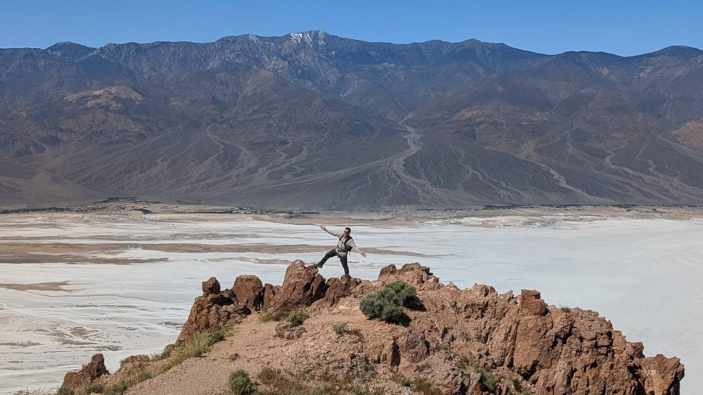 Visitor posing above Badwater Basin with dramatic mountain views in Death Valley National Park.