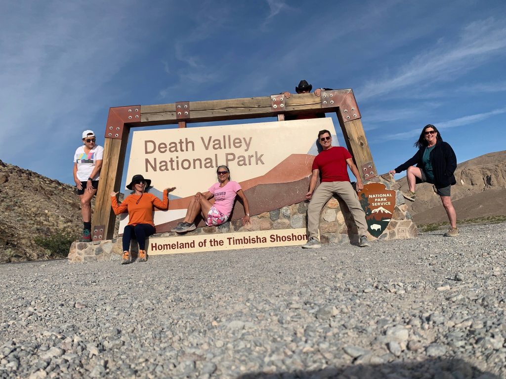 Group posing at the Death Valley National Park entrance sign in the California desert.