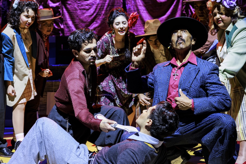 Raúl Cardona as El Pachuco leads an intense dramatic scene surrounded by cast members in Los Angeles Mission College’s vibrant production of Zoot Suit by Luis Valdez.