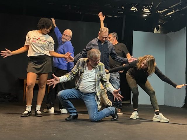 Cast members performing energetic ensemble choreography during Theatre West rehearsal for Broadway Bound