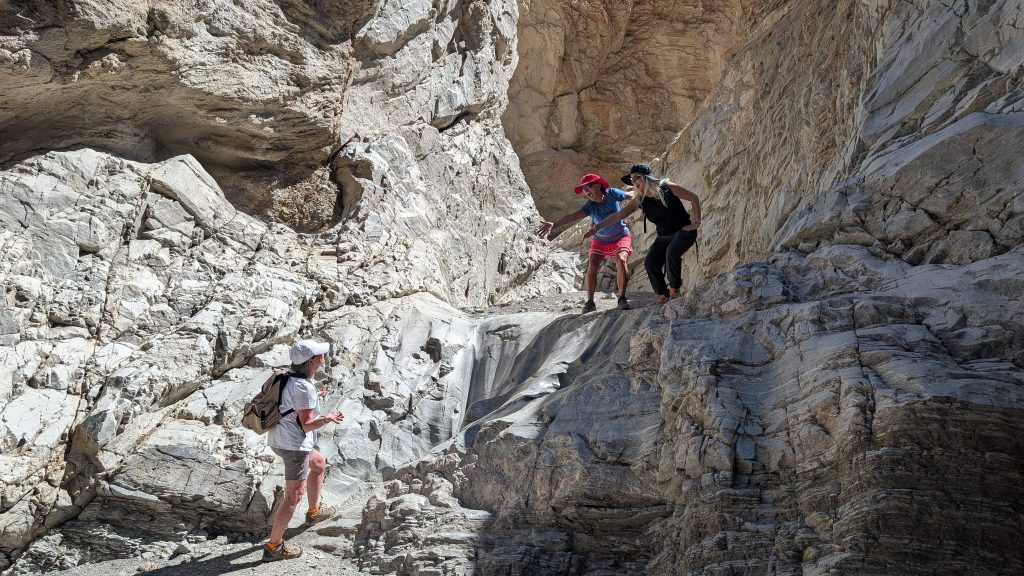 Hikers navigating the polished marble walls and rocky terrain of Mosaic Canyon in Death Valley National Park.