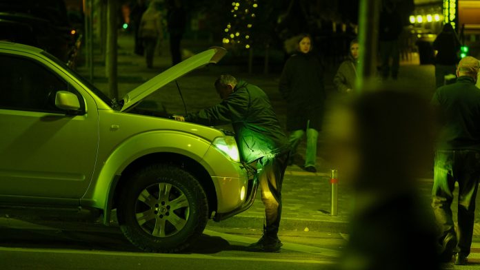 man inspecting car engine at night possible vehicle defect lemon law issue