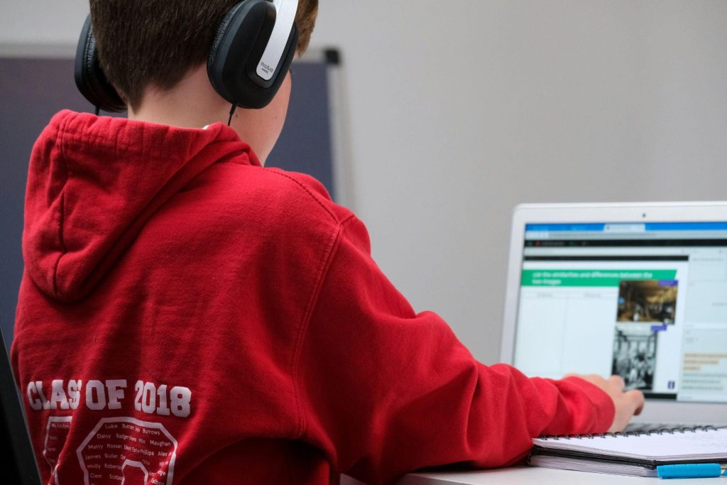 Student using headphones while completing online reading practice exercises on a laptop at home.