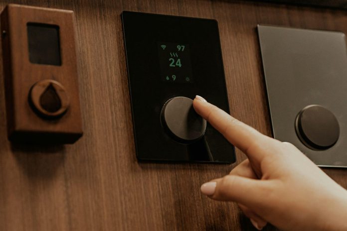 image Person adjusting a smart thermostat touch panel for automated home temperature control and energy efficiency.