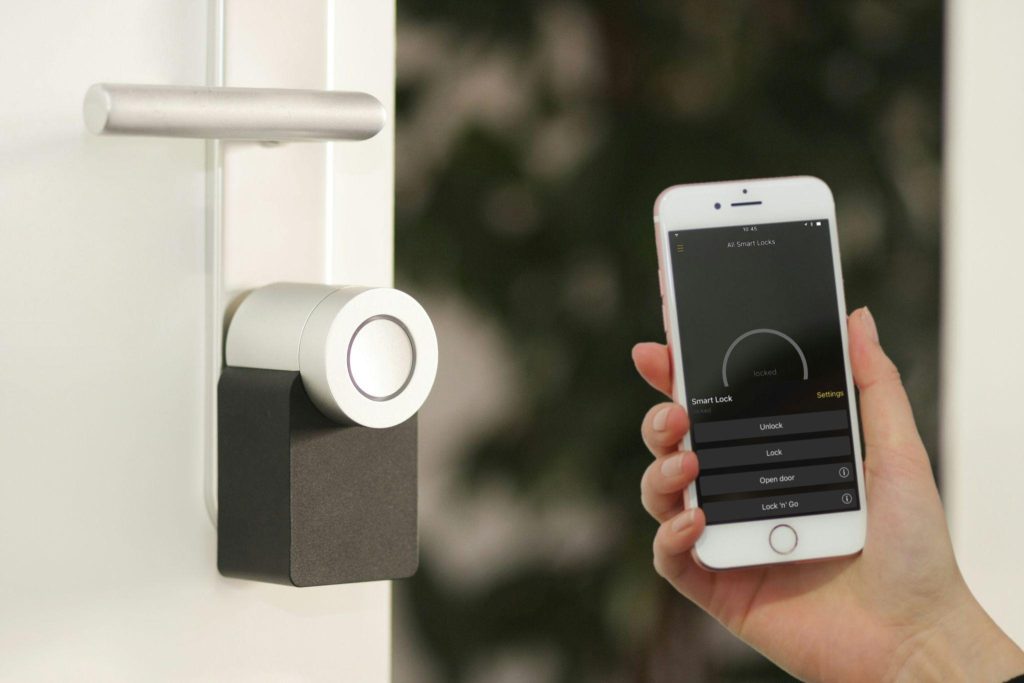 Smartphone controlling a smart door lock through a home automation app during secure home access.
