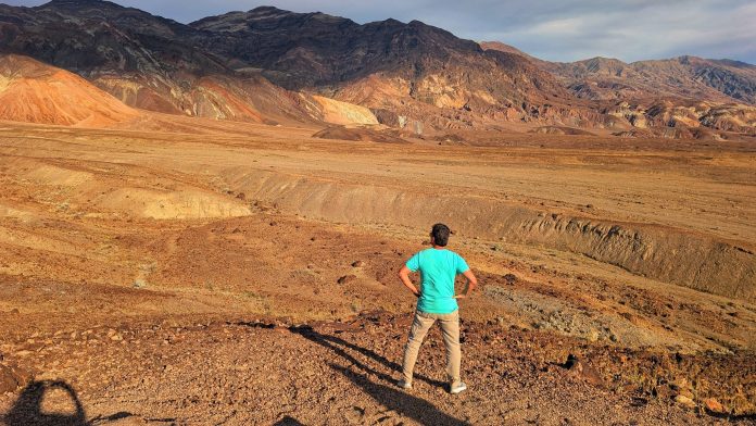 Traveler overlooking the colorful desert landscape and mountains of Death Valley National Park.