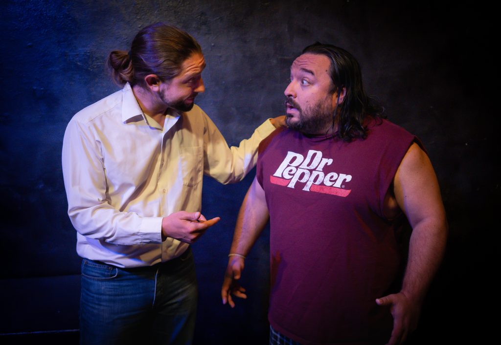 Actor in white shirt confronts castmate in Dr Pepper shirt during a scene from Something Anxious: A Double Feature at Hollywood Fringe 2026