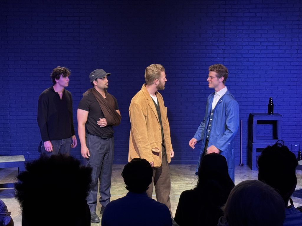 Actors perform an emotional scene from We Are All Burning, highlighting the play's themes of technology, labor and human connection.