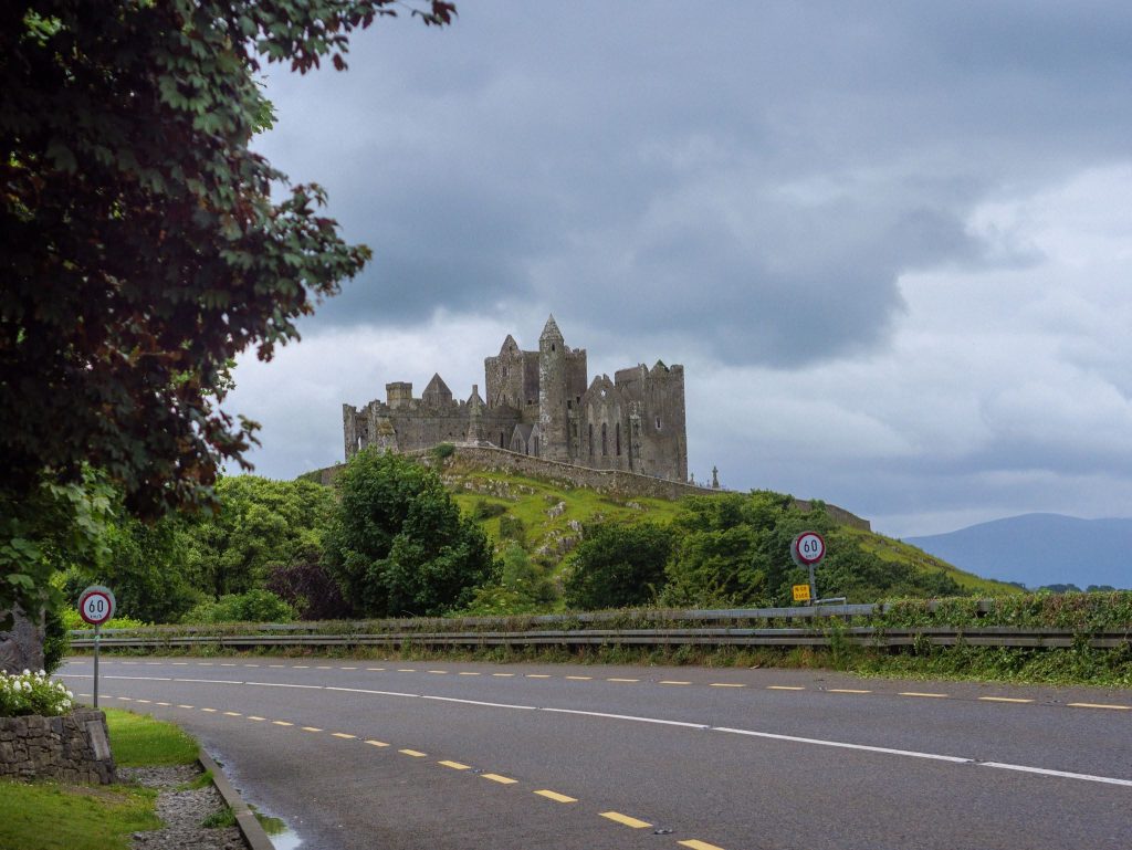 The Rock of Cashel rises above the Irish countryside under dramatic storm clouds in County Tipperary, Ireland.