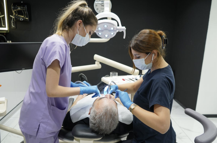 Screen Shot 2026-06-15 at 10.35.51 AM Dentists performing a dental filling procedure on a patient during a restorative dental treatment to repair tooth decay and protect long-term oral health.