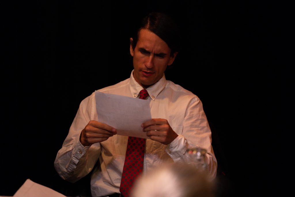 Actor reviews classified documents in a suspenseful scene from A Haunting Revue II