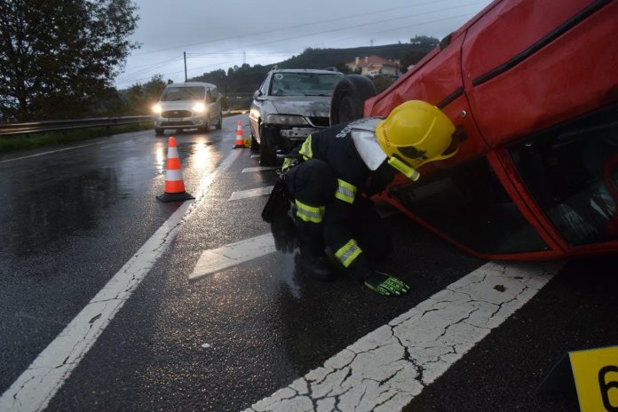Emergency responders inspecting an overturned vehicle after a serious car accident on a rain-soaked highway.