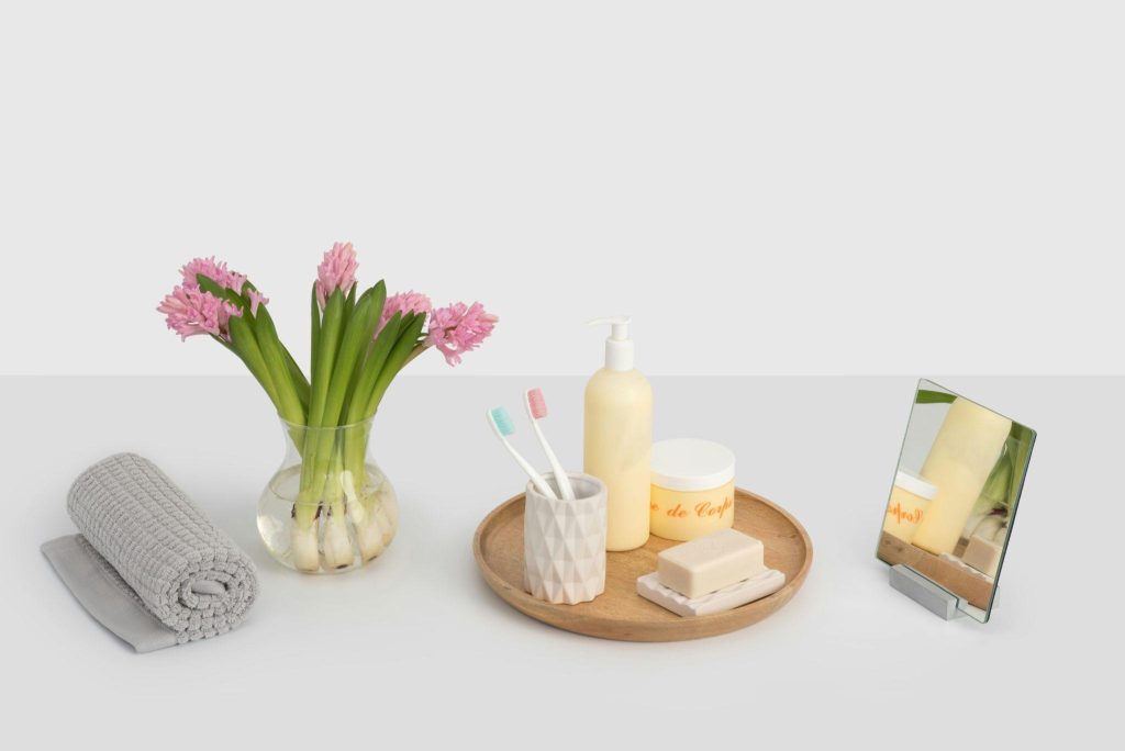 Self-care and beauty essentials including skincare products, towels, flowers, and grooming tools for an at-home beauty routine.