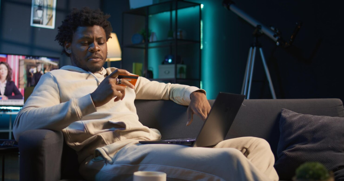 Sports bettor checks odds on a smartphone while using a laptop to compare online sports betting platforms and live markets.