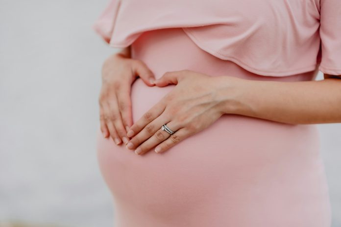 Pregnant woman gently holding her baby bump, representing maternal health and the importance of oral health during pregnancy.