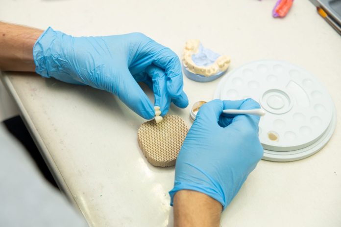 Dental technician creating a custom dental bridge in a dental laboratory before the final restoration is fitted.