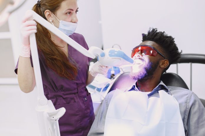 Dentist performing a professional teeth whitening treatment with an LED whitening system during a cosmetic dental visit.