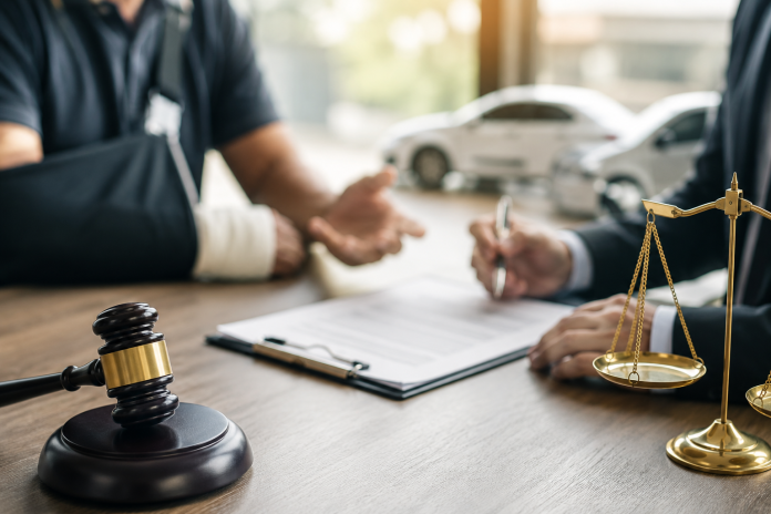 Personal injury attorney meeting with an injured client while reviewing documents, with a judge's gavel, scales of justice, and blurred vehicles symbolizing witness evidence in an accident claim.