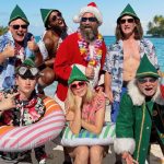 Cast of the Santasia Summer Sing-Along poses in Santa hats, elf costumes, Hawaiian shirts, and beach floats for a Christmas in July celebration.