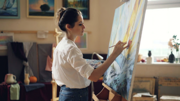 Artist painting on a large canvas in a bright studio, illustrating how digital technologies continue to reshape creativity and the visual arts.