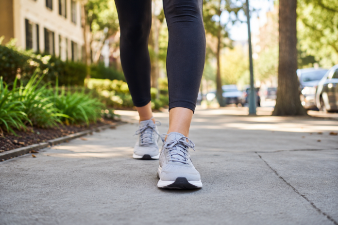 Woman wearing comfortable walking shoes on a sunny city sidewalk.
