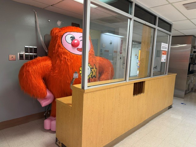 Large orange furry character peeking into a former hospital nurses' station.