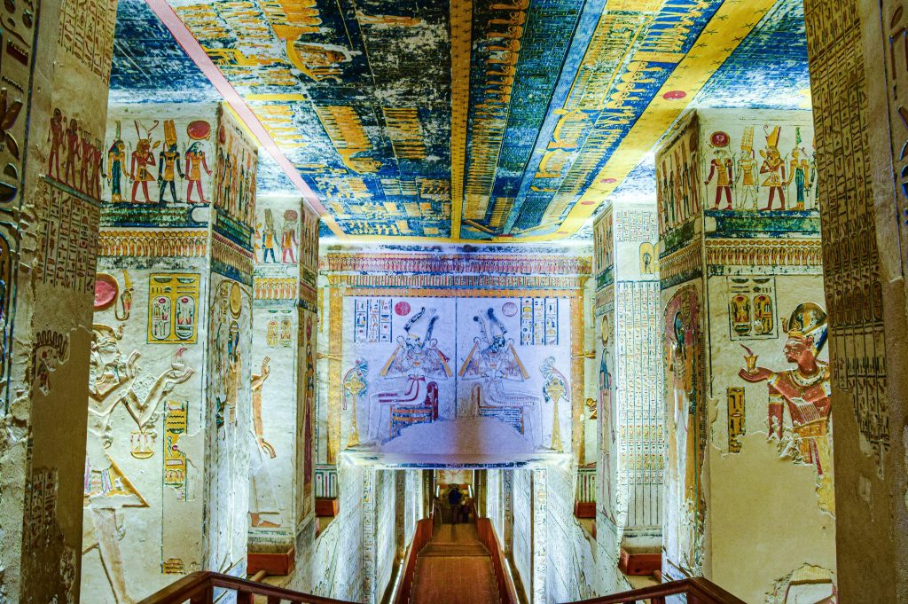 Colorful hieroglyphs and ancient Egyptian artwork cover the walls and ceiling inside a richly decorated temple in Luxor, Egypt.