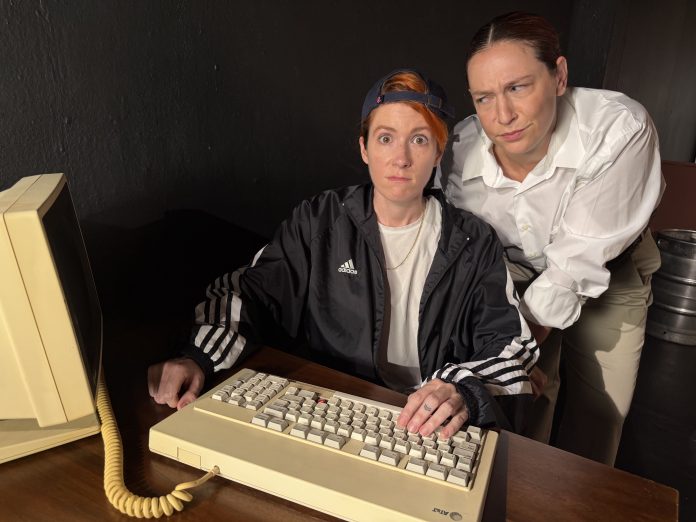Genevieve Lerner and Spring Ferrara remain frozen in disbelief at a computer during a humorous moment in Matt & Ben at The Sherry Theater.