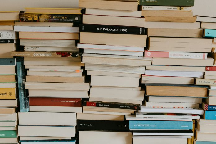 Stacks of books arranged in uneven piles, representing the mix of data, knowledge and instinct behind TACAW’s arts programming decisions.