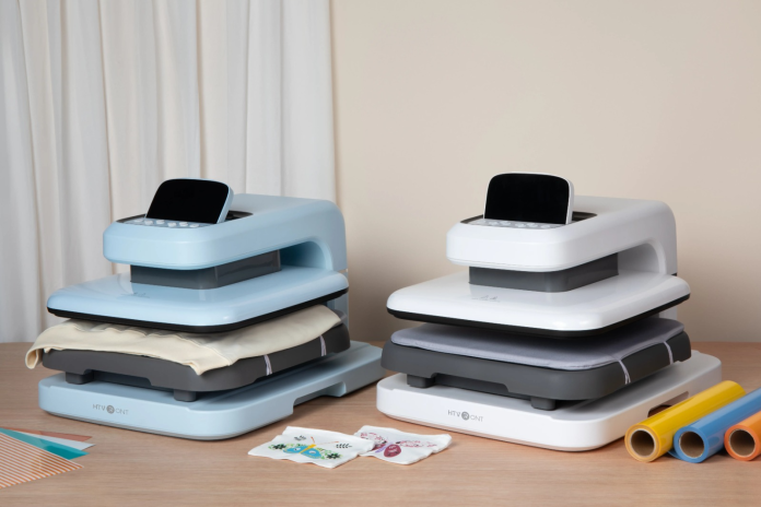 image Two compact heat press machines with colorful heat transfer vinyl and custom designs in a home crafting workspace.
