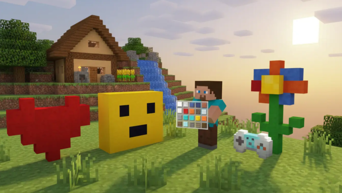 Minecraft player creating colorful pixel art beside a house with a heart, flower, emoji face, and game controller made from blocks.