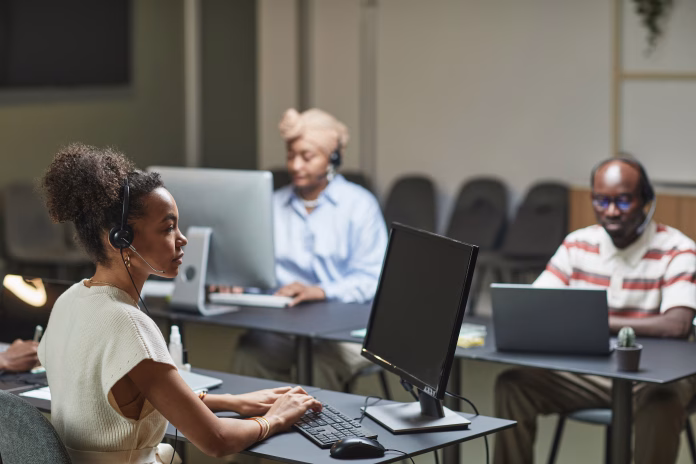 Call center representative wearing a headset while working alongside other customer service agents.