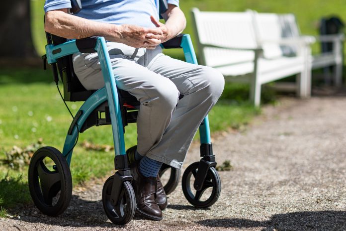 Person seated in a mobility wheelchair outdoors on a paved path, illustrating mobility support and accessible travel.