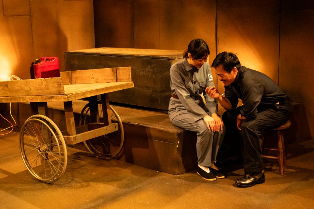 Alt text: Two characters during the Cultural Revolution scene in In the Tomb of Ten Thousand Calendars at Moving Arts Theatre.