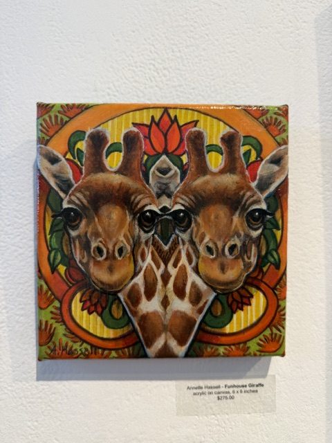 Colorful painting of two giraffes against an ornate orange, yellow and green patterned background at Laluzapalooza 2026.